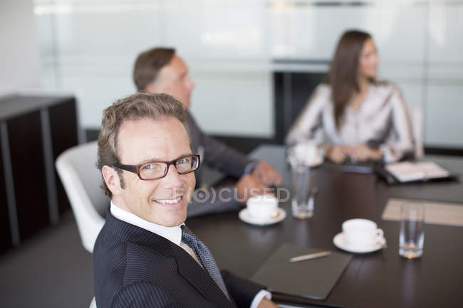 Empresario sonriendo en reunión en oficina moderna - foto de stock