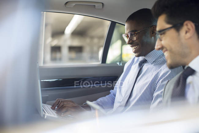 Les hommes d'affaires utilisant un ordinateur portable en voiture — Photo de stock