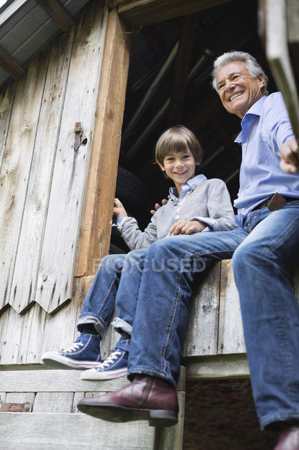 Homem e neto sentados à porta — Fotografia de Stock