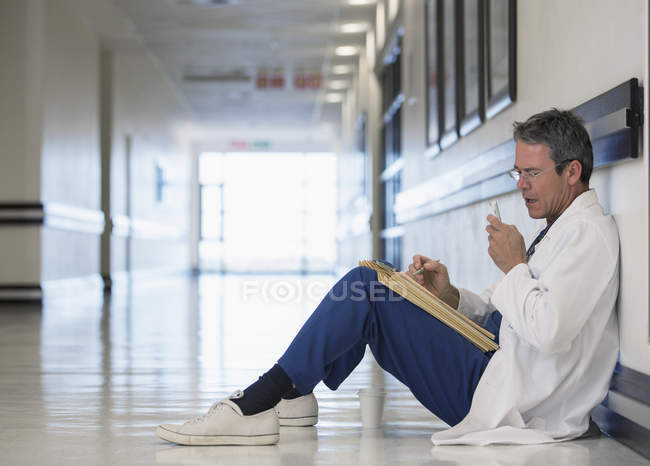 Medico che utilizza il dictaphone nel corridoio dell'ospedale — Foto stock