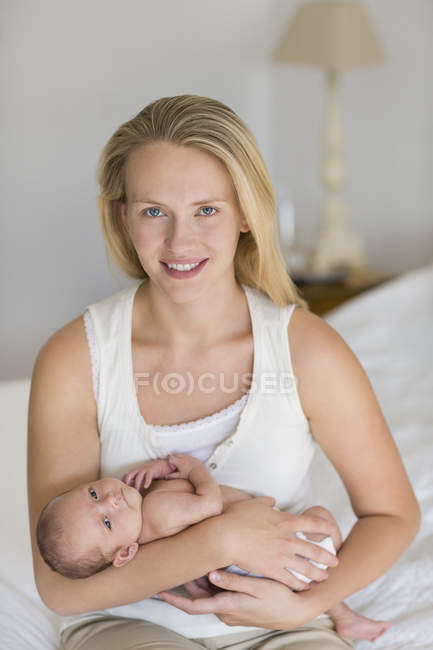 Mãe berço bebê recém-nascido na cama — Fotografia de Stock