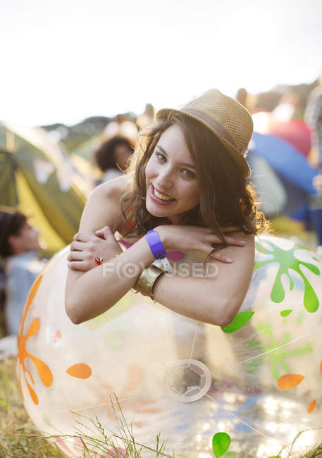 Portrait of happy woman leaning on inflatable chair outside tents at music festival — Stock Photo