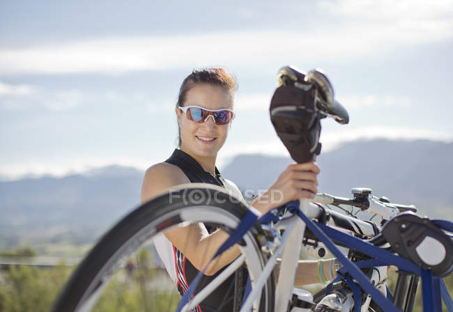 Mujer tomando bicicleta fuera de estante de bicicleta - foto de stock