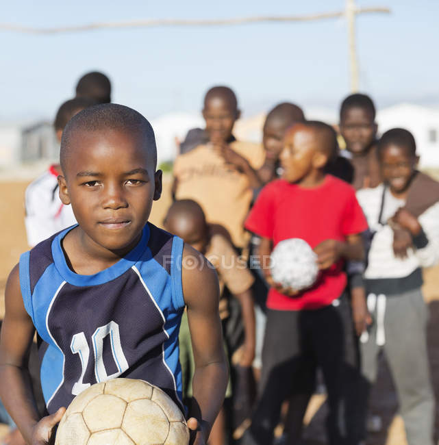Garçons africains tenant des balles de football dans un champ de terre — Photo de stock