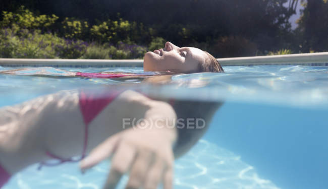 Seitenansicht einer im Schwimmbad treibenden Frau — Stockfoto