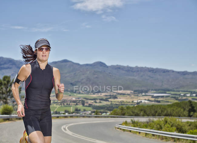 Mujer corriendo por carretera rural - foto de stock