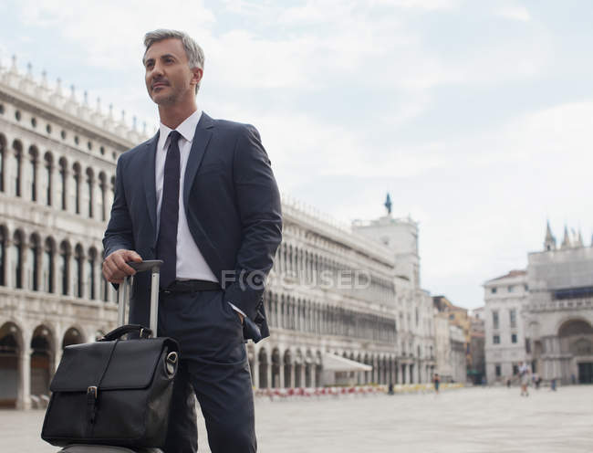 Confident businessman with briefcase and suitcase in St. Mark Square in Venice — Stock Photo