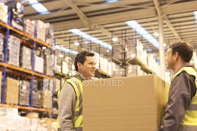Workers carrying box in warehouse — Stock Photo