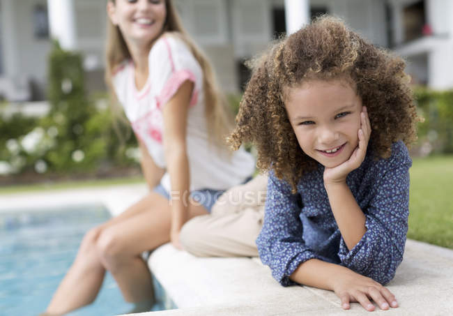 Mother and daughter relaxing by swimming pool — Stock Photo
