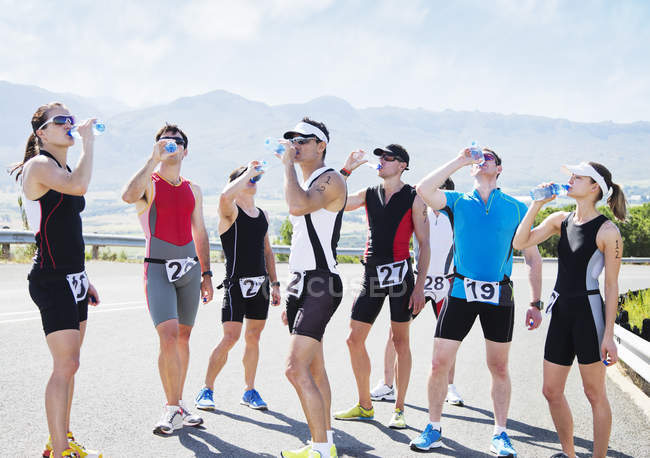 Runners drinking water on rural road — Stock Photo