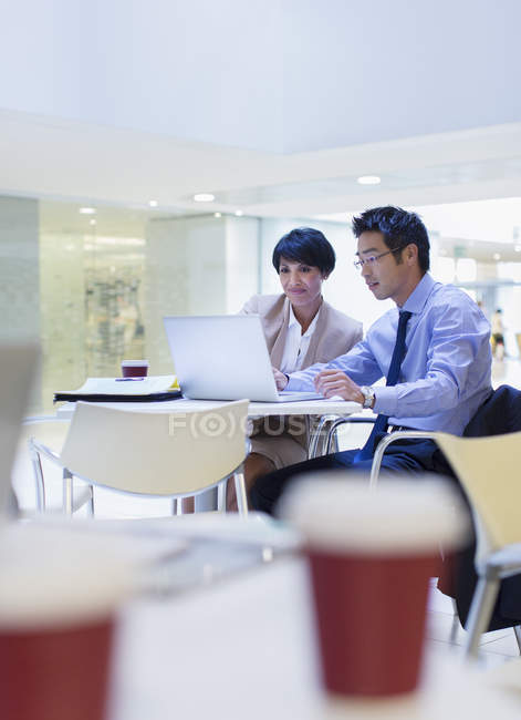 Business people using laptop at table in modern office building — Stock Photo