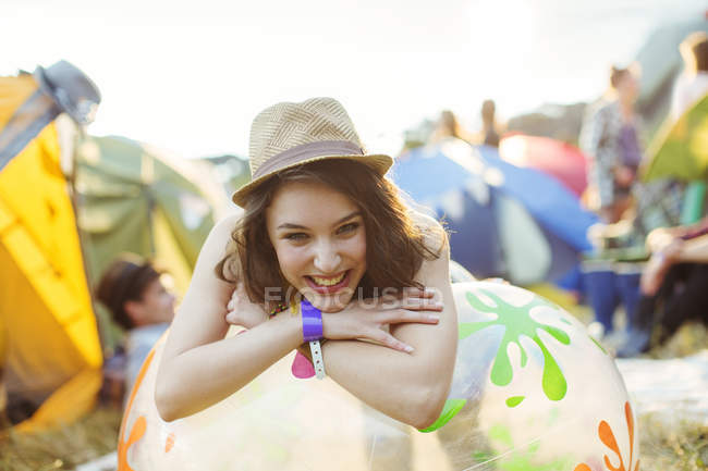 Retrato de una mujer sonriente apoyada en una silla inflable fuera de las carpas en el festival de música - foto de stock