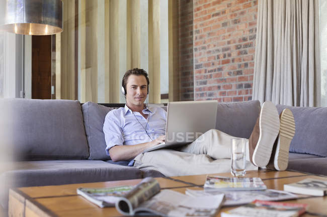 Mann benutzt Laptop auf Sofa — Stockfoto