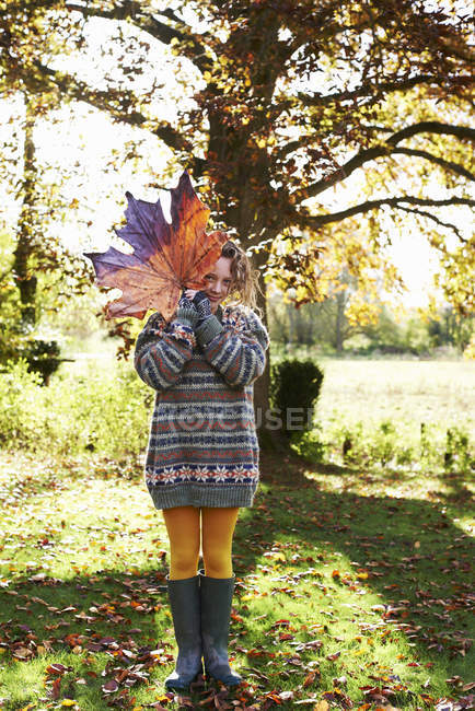 Ragazza che gioca con la foglia di autunno all'aperto — Foto stock