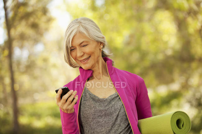Пожилая женщина использует мобильный телефон на открытом воздухе — стоковое фото