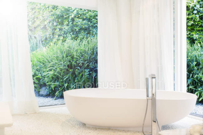 Bathtub, curtain, and windows in modern bathroom — Stock Photo