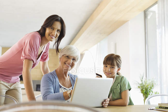 Tres generaciones de mujeres usando el ordenador portátil juntas - foto de stock