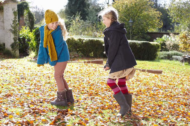 Chicas jugando juntas en hojas de otoño - foto de stock