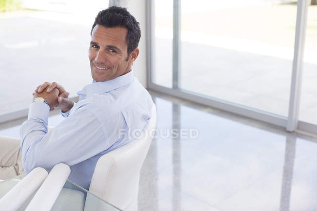 Uomo d'affari caucasico sorridente in sedia ufficio — Foto stock