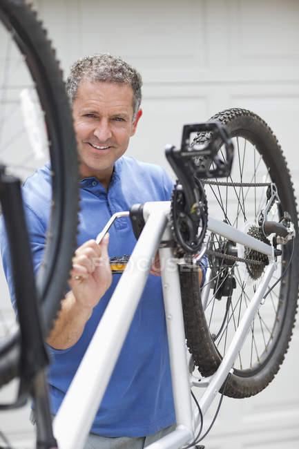 Skillful caucasian man working on bicycle in driveway — Stock Photo