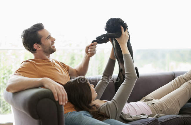 Пара розслабляється з собакою на дивані в сучасному будинку — стокове фото