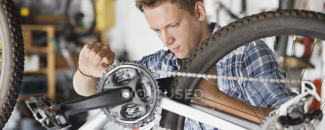 Skillful caucasian man working on bicycle in shop — Stock Photo