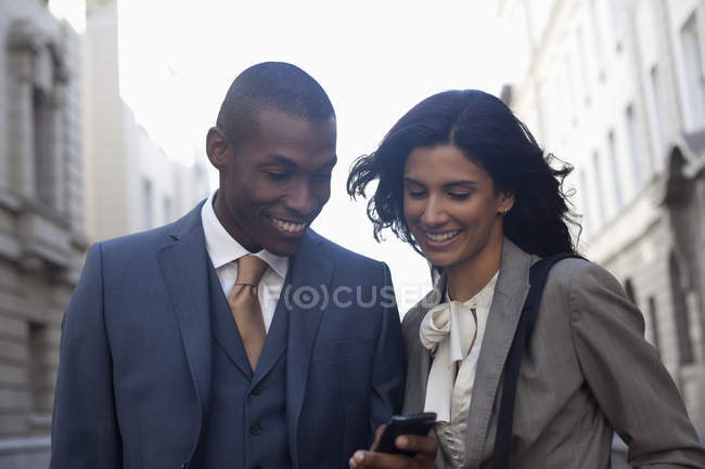 Mensajería de texto de gente de negocios sonriente con teléfono celular - foto de stock