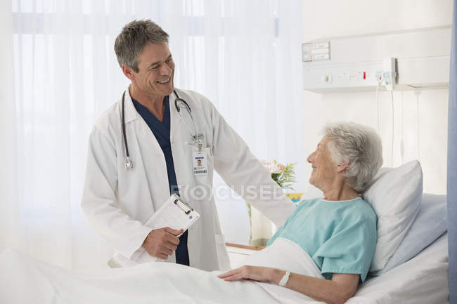 Doctor talking to elderly patient in hospital — Stock Photo