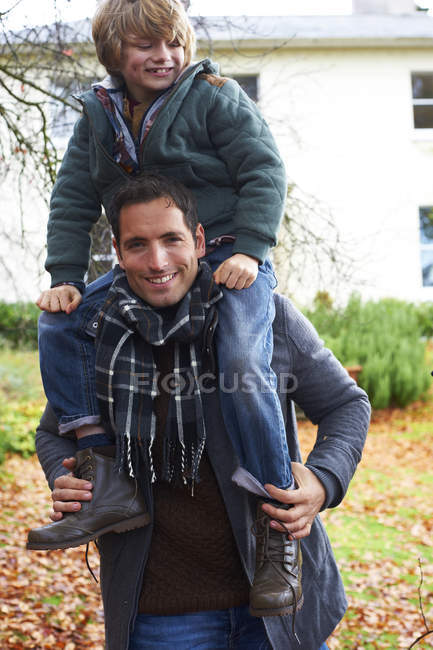 Father carrying son on shoulders outdoors — Stock Photo