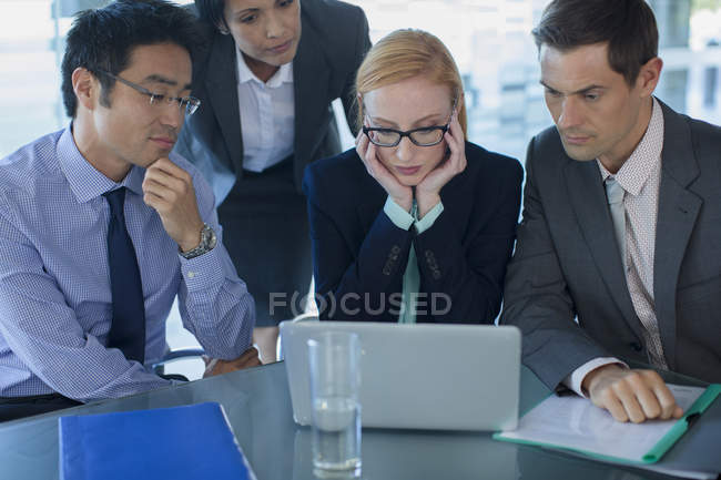 Business people gathered around laptop at table in office building — Stock Photo