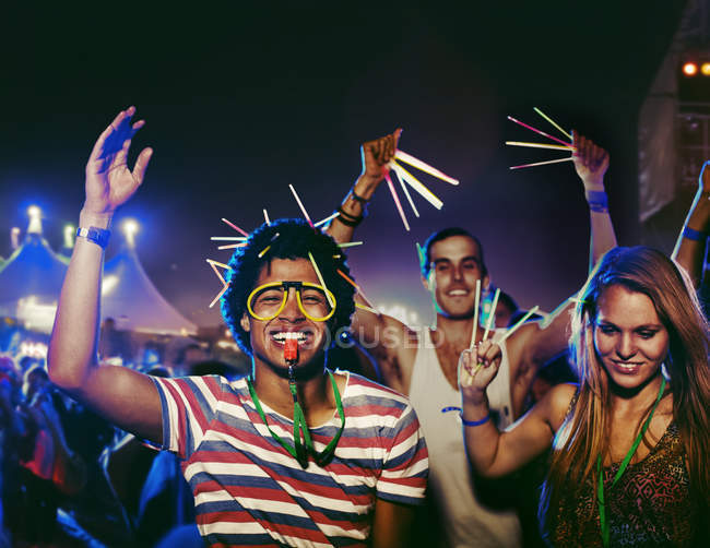 Aficionados con palos brillantes animando en el festival de música - foto de stock