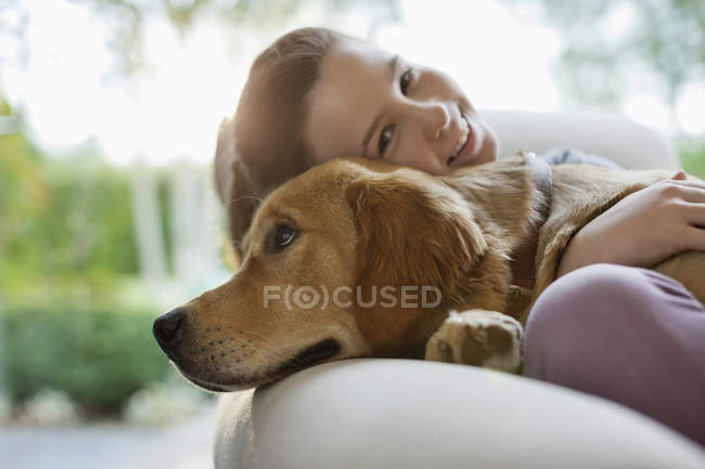 Дівчина розслабляється з собакою на дивані в сучасному будинку — стокове фото
