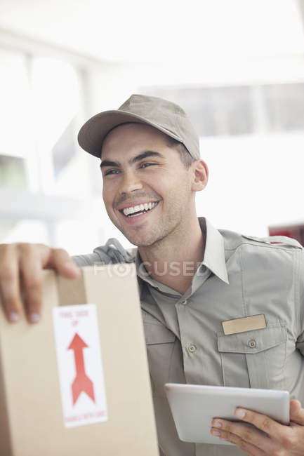 Delivery boy using tablet computer at modern office — Stock Photo