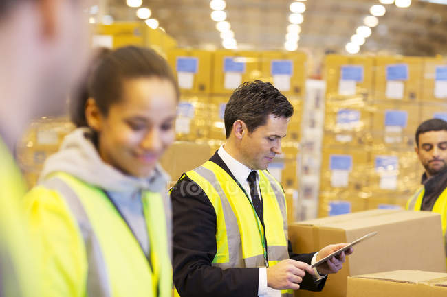 Businessman and workers in warehouse — Stock Photo