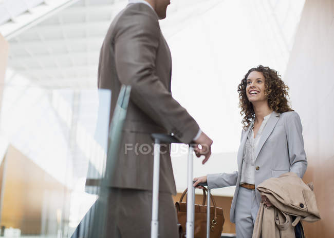 Lächelnde Geschäftsfrau im Gespräch mit Geschäftsmann am Flughafen — Stockfoto