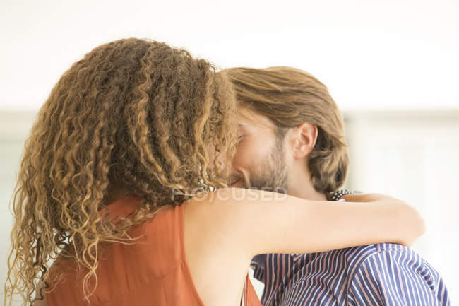 Молодая привлекательная пара целуется в помещении — стоковое фото