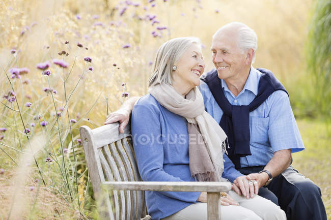 Старшая пара отдыхает на скамейке в парке — стоковое фото