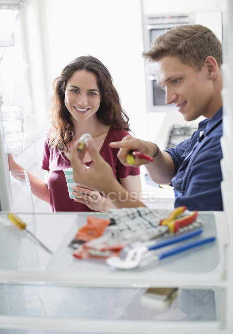 Skillful caucasian electrician talking to client in kitchen — Stock Photo