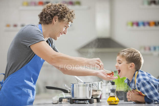 Padre e hijo cocinando en la cocina - foto de stock