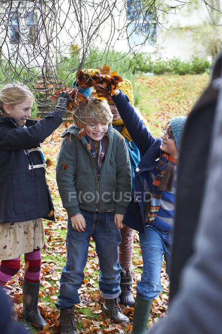 Children playing in autumn leaves outdoors — Stock Photo