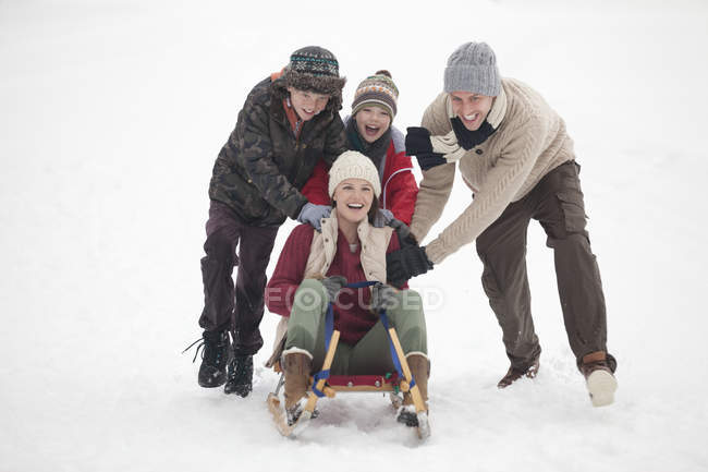 Happy family sledding in snow — Stock Photo