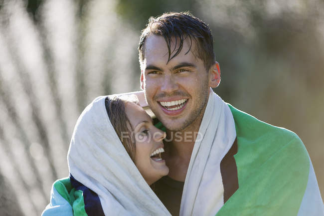 Happy couple wrapped in towel outdoors — Stock Photo