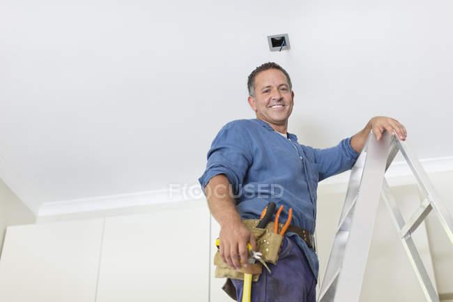 Homem caucasiano hábil trabalhando em luzes de teto — Fotografia de Stock