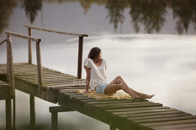 Mulher sentado na doca sobre o lago — Fotografia de Stock