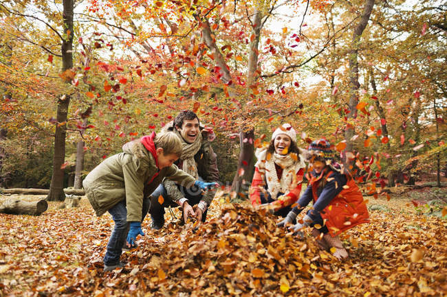 Familia feliz jugando en hojas de otoño - foto de stock