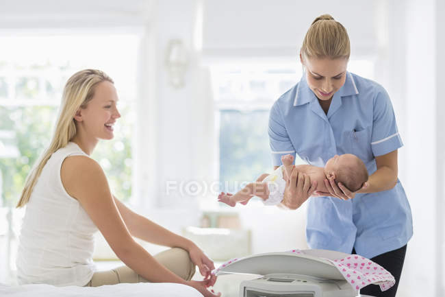 Nurse helping mother with newborn baby — Stock Photo