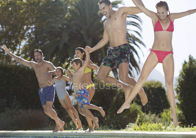 Happy family jumping into swimming pool — Stock Photo