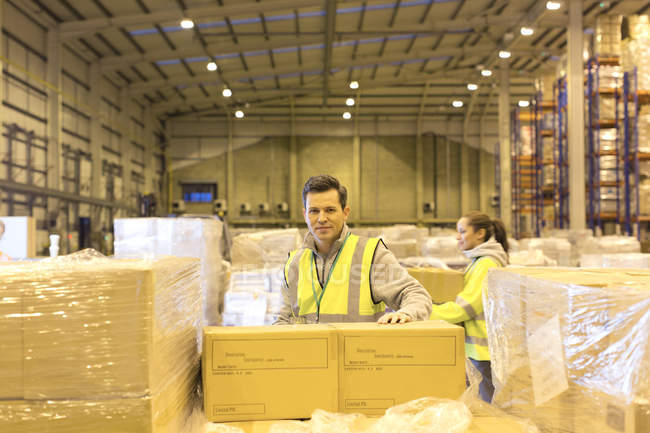 Trabalhador desembalagem caixas no armazém — Fotografia de Stock