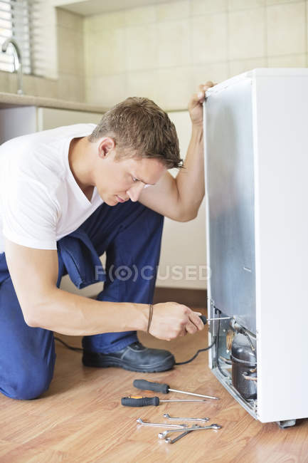 Hábil reparador caucásico trabajando en electrodomésticos en la cocina - foto de stock