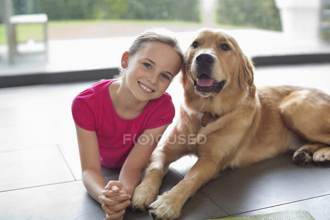 Улыбающаяся девушка отдыхает с собакой в помещении — стоковое фото